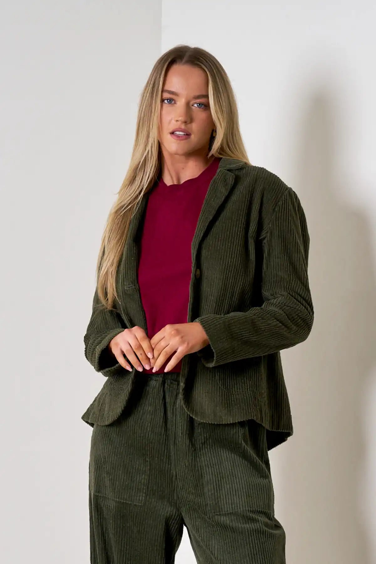 Woman wearing Baltic Corduroy Jacket in Forest with a red shirt against a white background