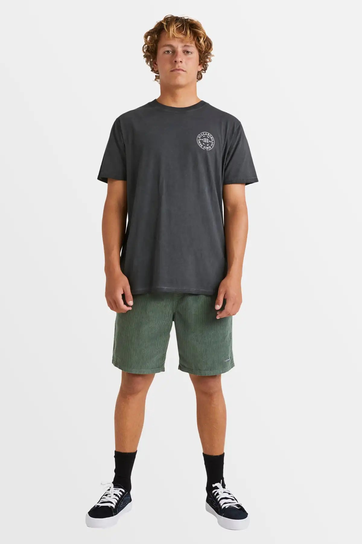 Person wearing a dark gray t-shirt and green shorts on a white background