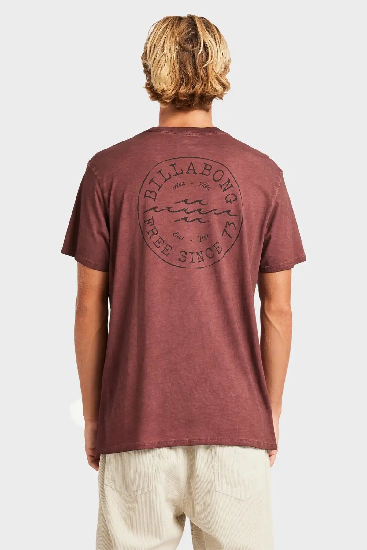Person wearing a maroon Billabong t-shirt with a logo on the back against a white background