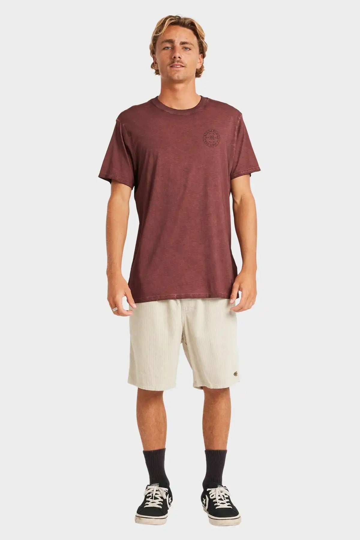 Man wearing a brown t-shirt and beige shorts on a white background