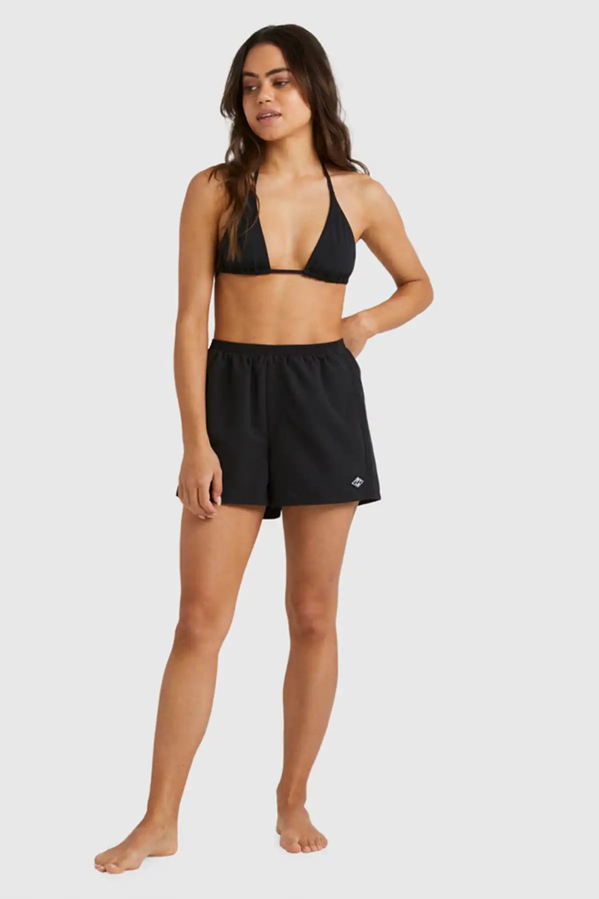 Woman wearing a black bikini top and Billabong Womens Sandbar Boardshorts set on a white background