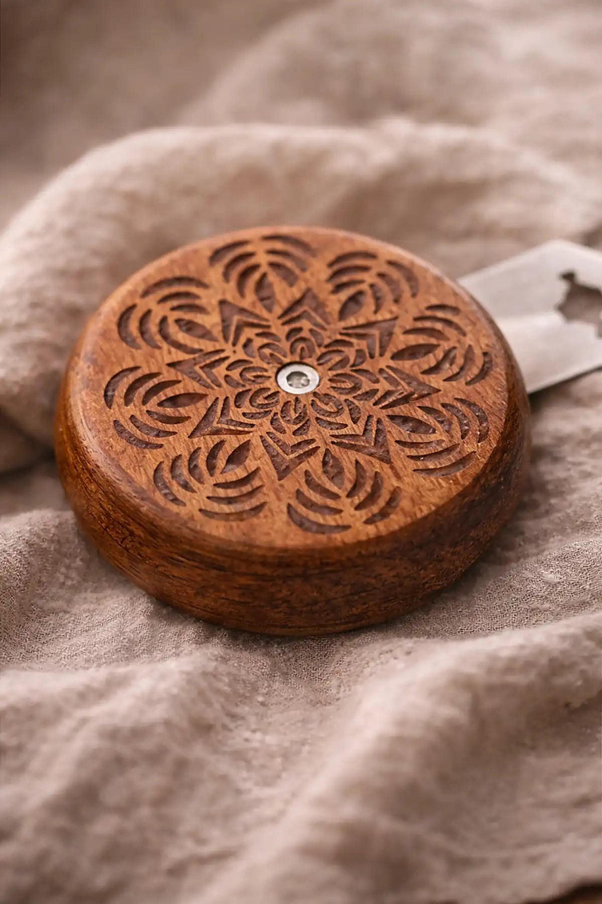 Wooden bread lame with intricate carvings on a textured fabric background