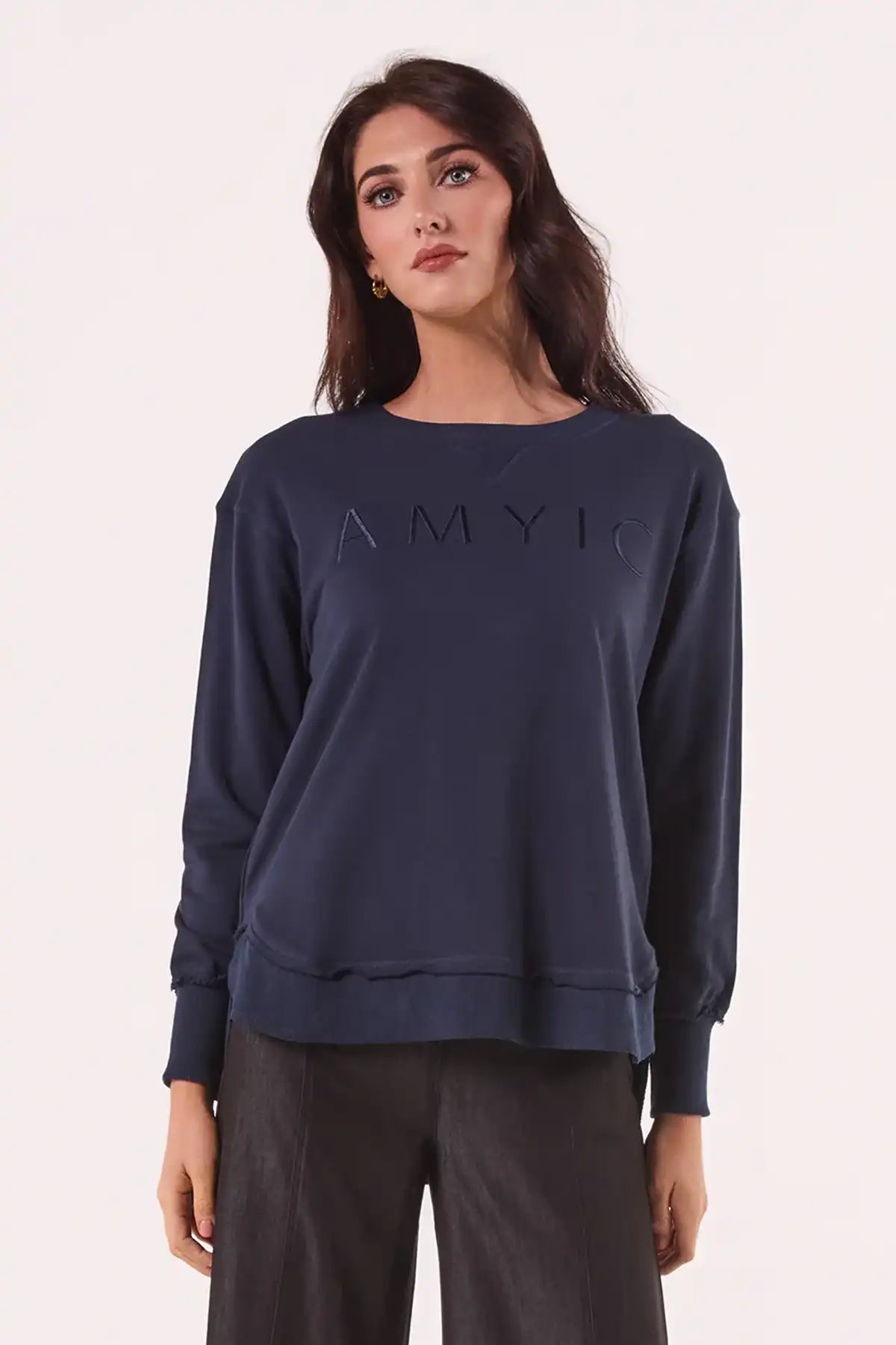 Woman wearing a Chille Everyday Wander Pullover in Navy with 'AMY' logo on a light pink background front on view