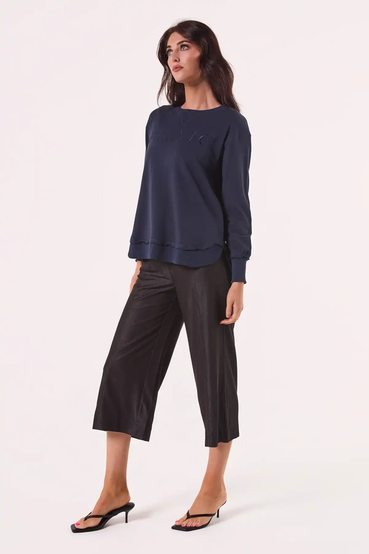 Woman wearing a Chille Everyday Wander Pullover in Navy and black pants on a white background side view