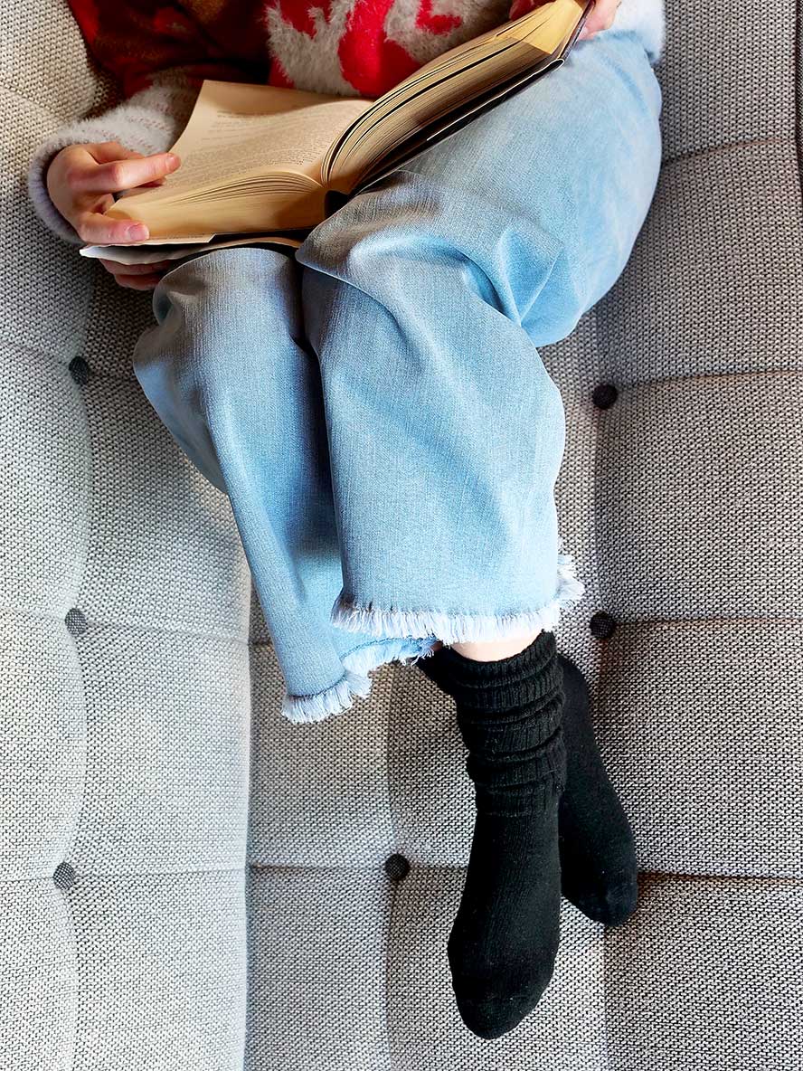 model on coach with book wearing Chille Wool Blend Socks in Black