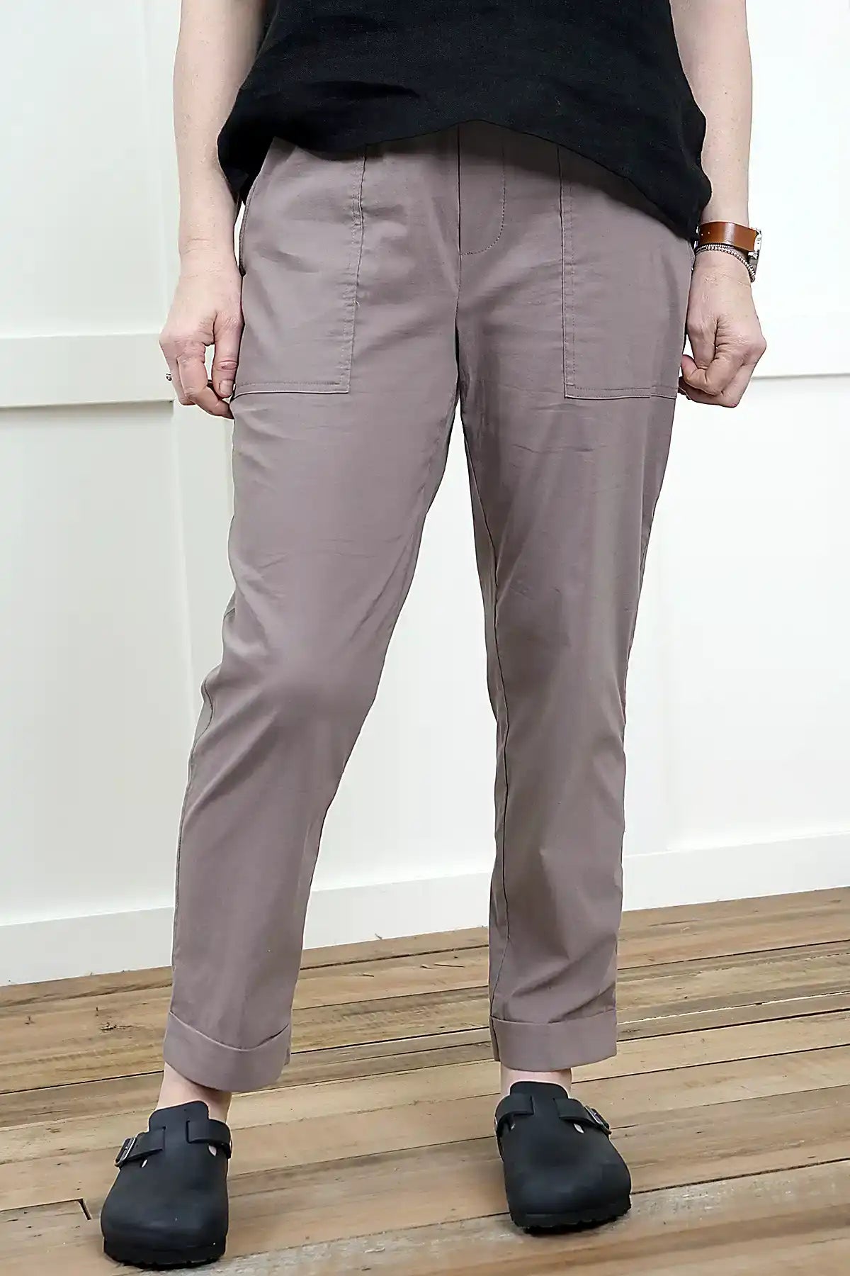 Person wearing Clara Cotton Blend Pull-On Pants in Mushroom and black shoes on a wooden floor with a white wall background