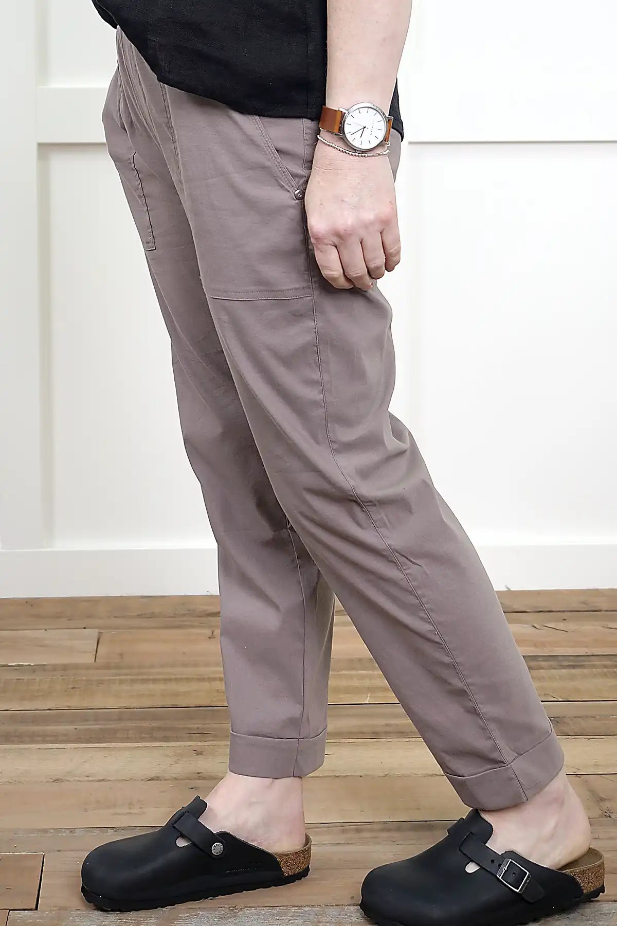 Person wearing Clara Cotton Blend Pull-On Pants in Mushroom from the side view and black clogs on a wooden floor.