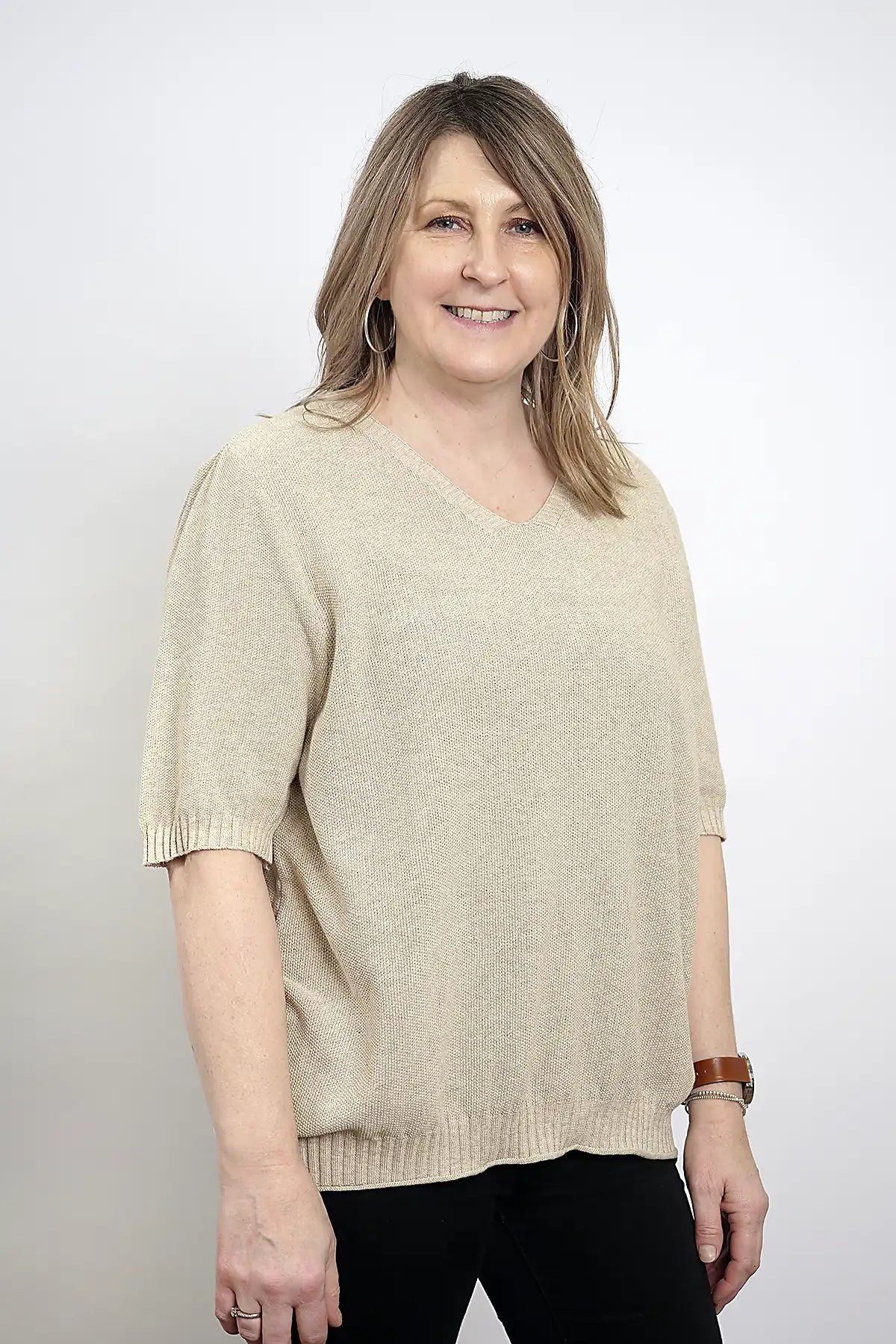 Woman wearing a Coastal Ease Cotton Knit Tee in Sand against a white background side view