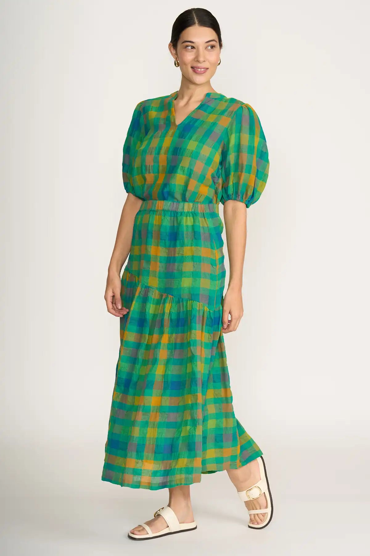 Woman wearing a Foil Checkmate Cotton Linen Skirt in Greencheck against a white background 3/4 side view