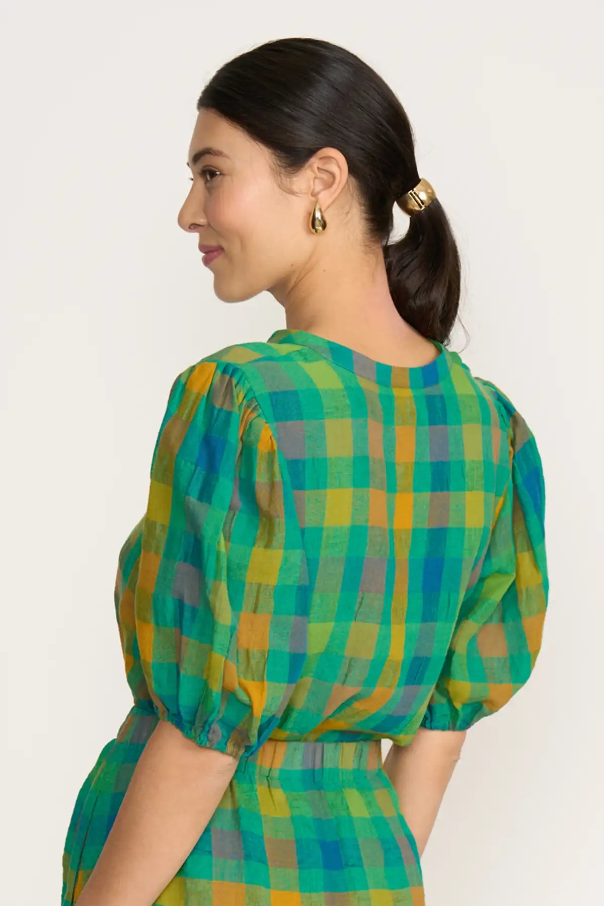 Woman wearing a Foil Checkmate Top – Green Check against a white background back view
