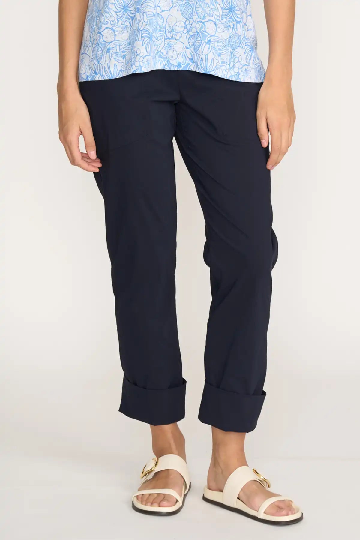 Person wearing Foil Gemini Pant – True Navy and a light blue floral top on a white background front detailed view with cuff rolled up
