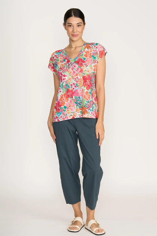Woman wearing a colorful floral top and Foil Gemini Pants in Basalt on a white background