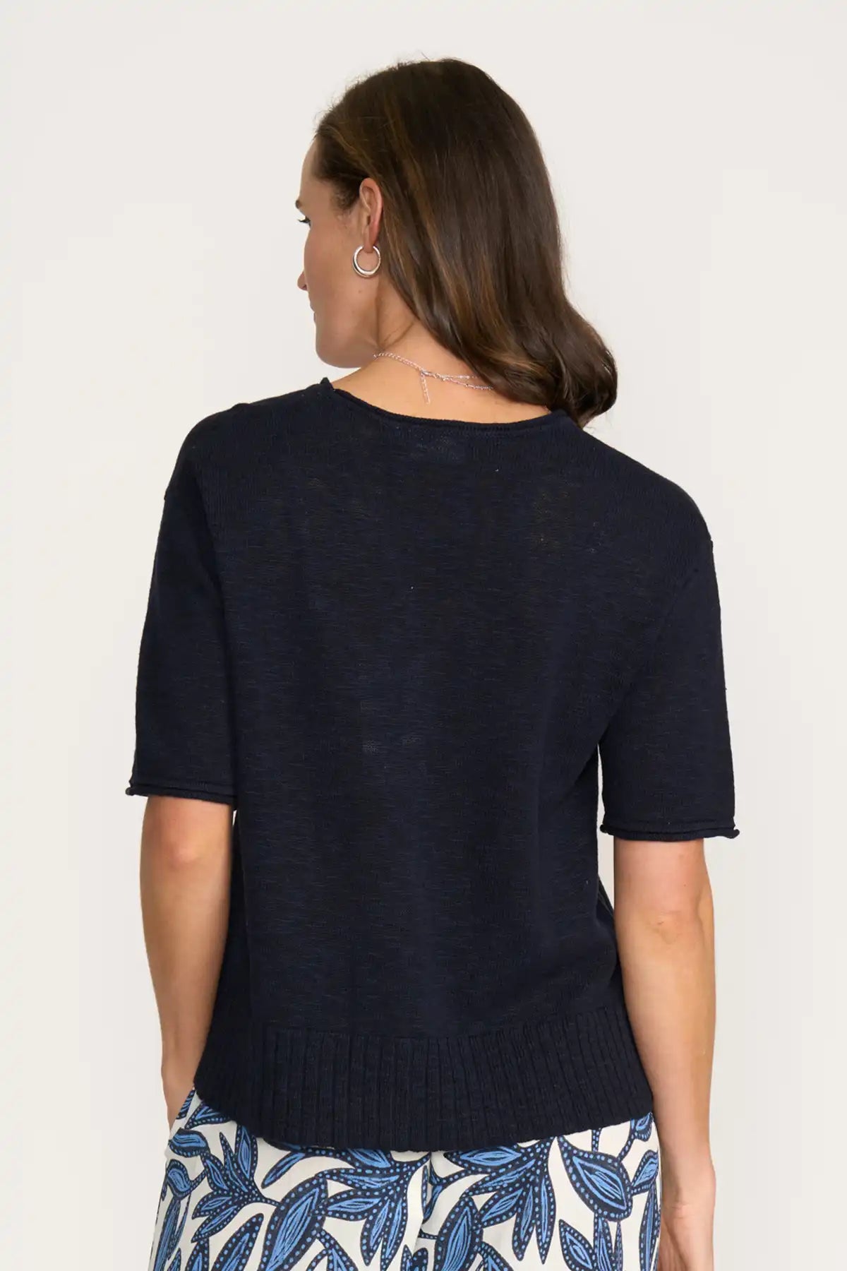 Woman wearing a Foil Nitty Gritty Cardigan in True Navy with a plain background back view