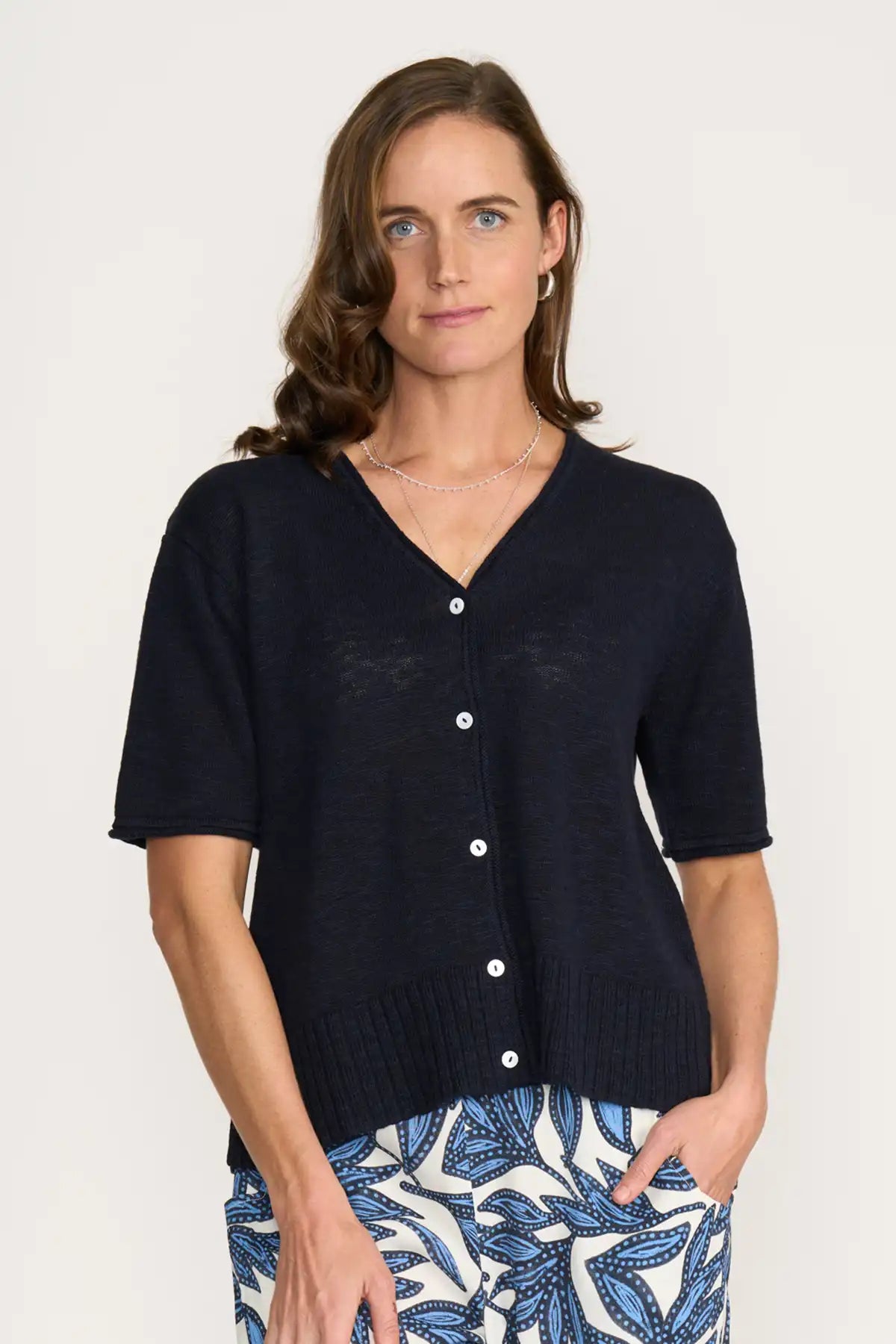 Woman wearing a Foil Nitty Gritty Cardigan in True Navy over a patterned skirt on a white background