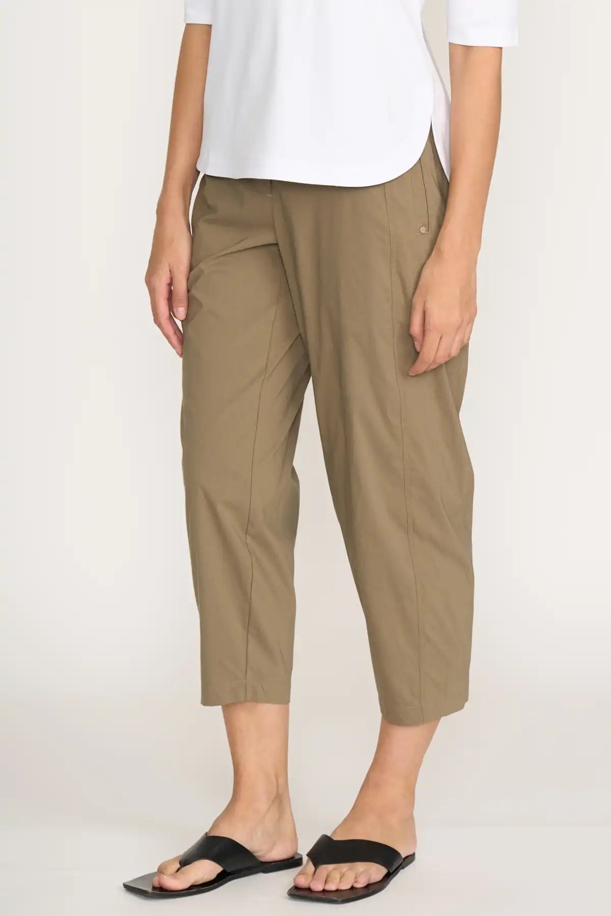 Person wearing Foil Pump it Up Pant in Dune and a white shirt on a plain background side view with hand out of pocket