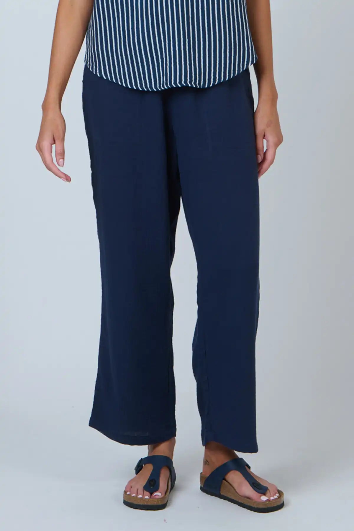 Person wearing navy pants and a striped top on a white background