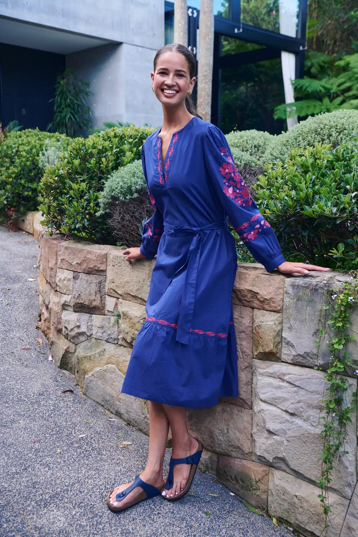 woman wearing Ink Rose Embroidered Midi Dress standing against rock wall in garden