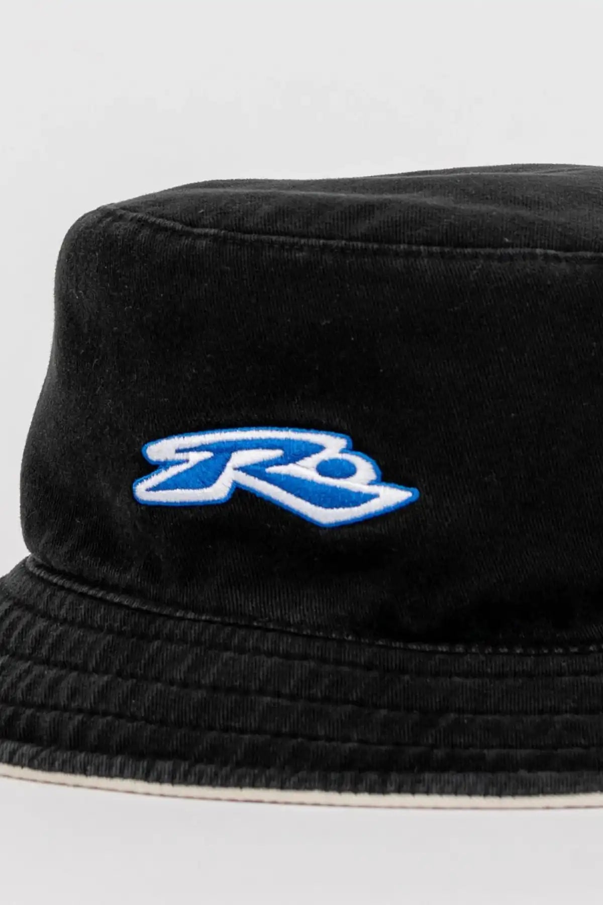 Rusty Kick Flip Reversible Bucket Hat showing washed black side with a blue logo on a white background