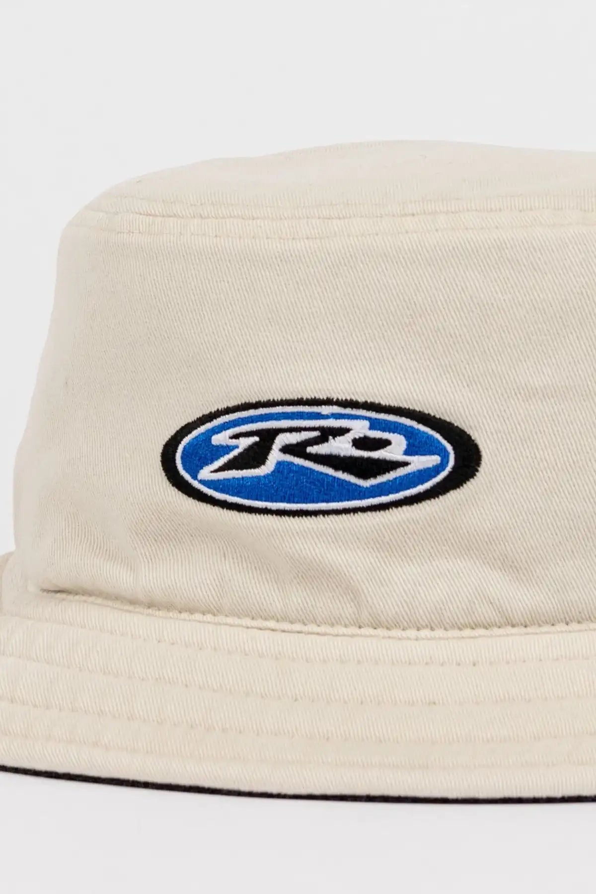 Rusty Kick Flip Reversible Bucket Hat showing oatmeal side with a logo on a white background
