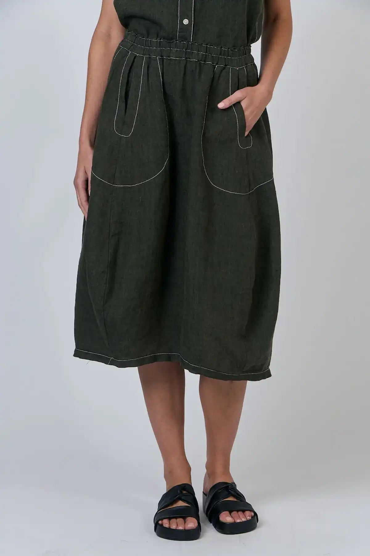 Person wearing a Licorice Linen Skirt with hand in pocket on a white background