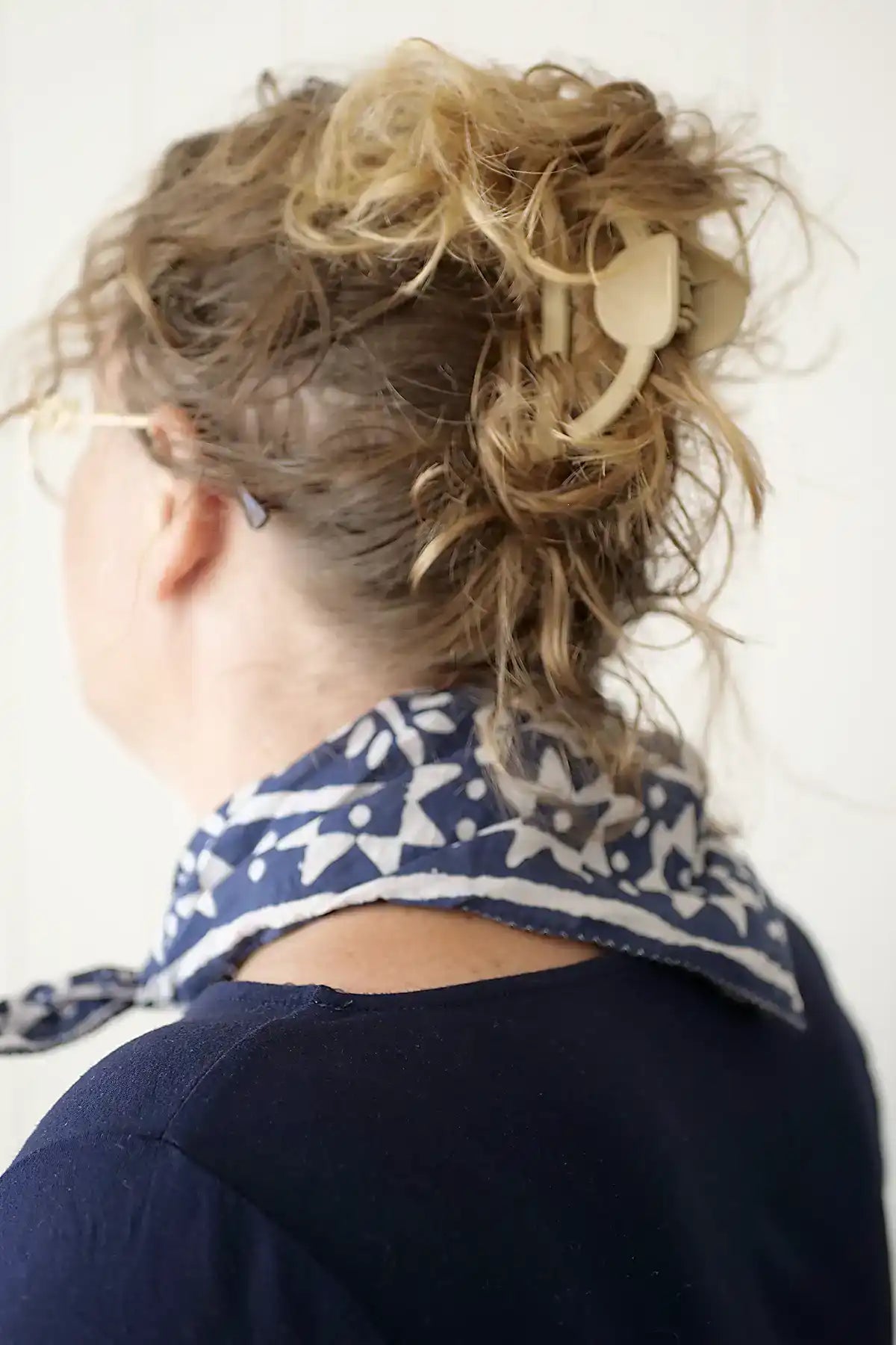 Person with messy bun wearing a blue patterned scarf on a white background