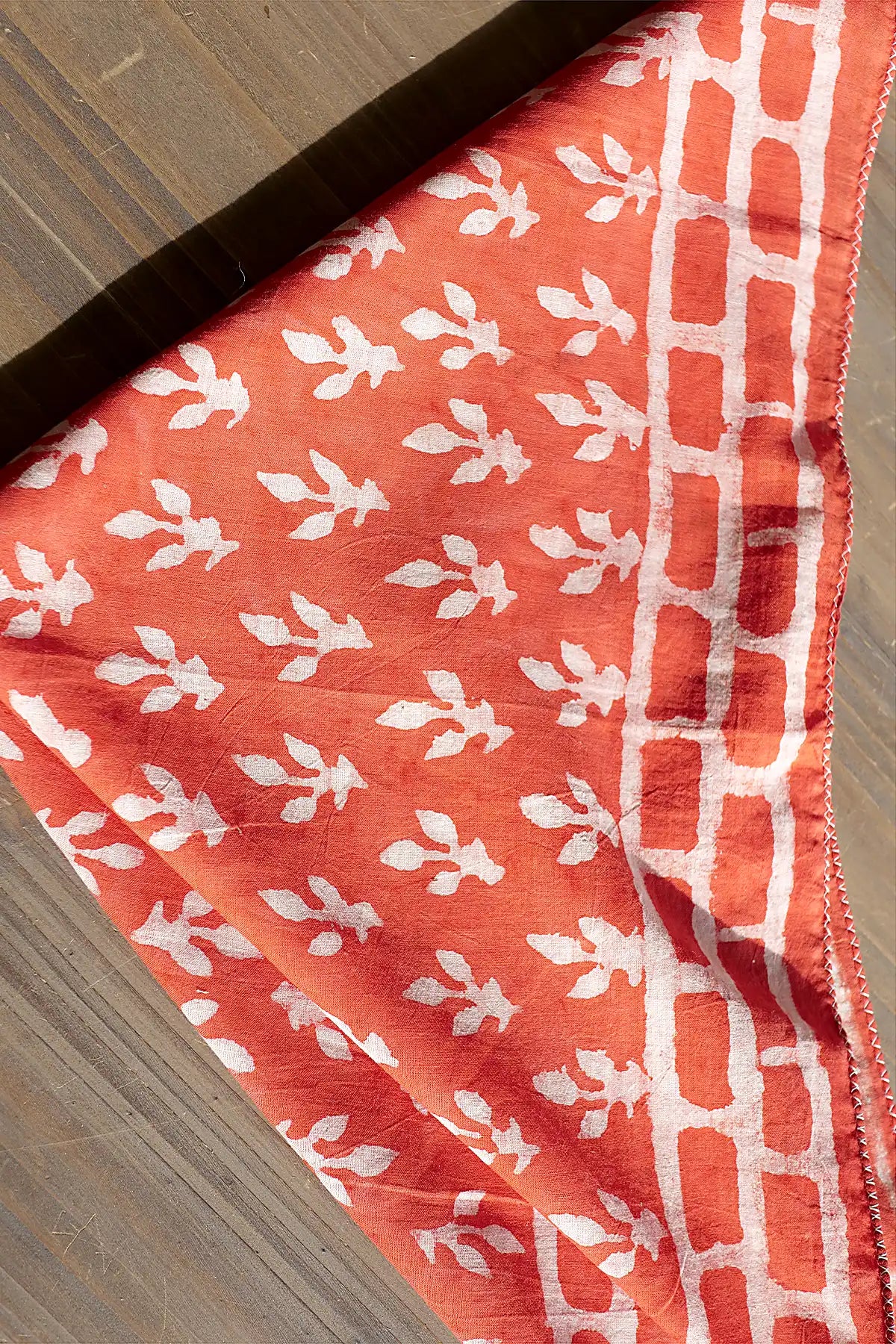 Coral fabric scarf with white floral pattern on a wooden surface