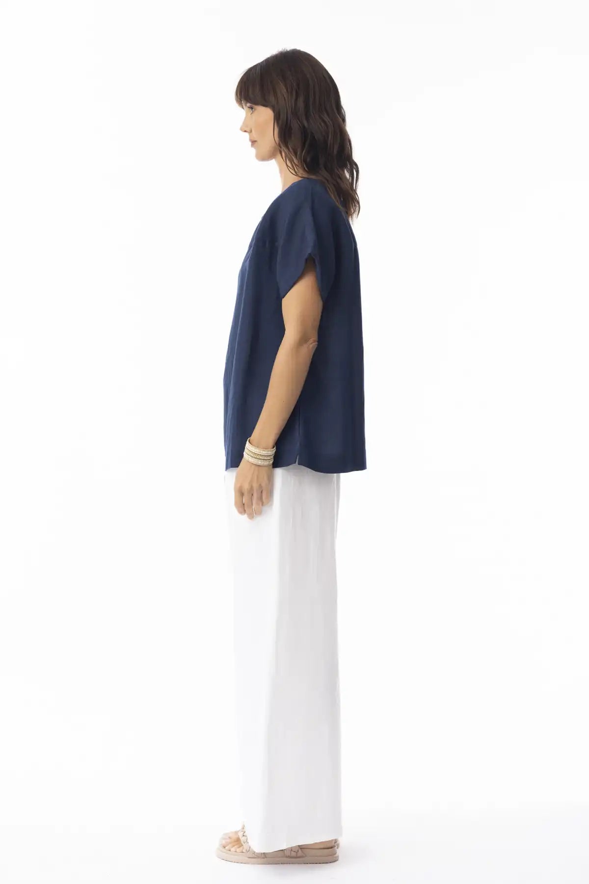 Woman wearing a Orientique Escape Linen Solid Boxy Navy Top and white pants on a white background