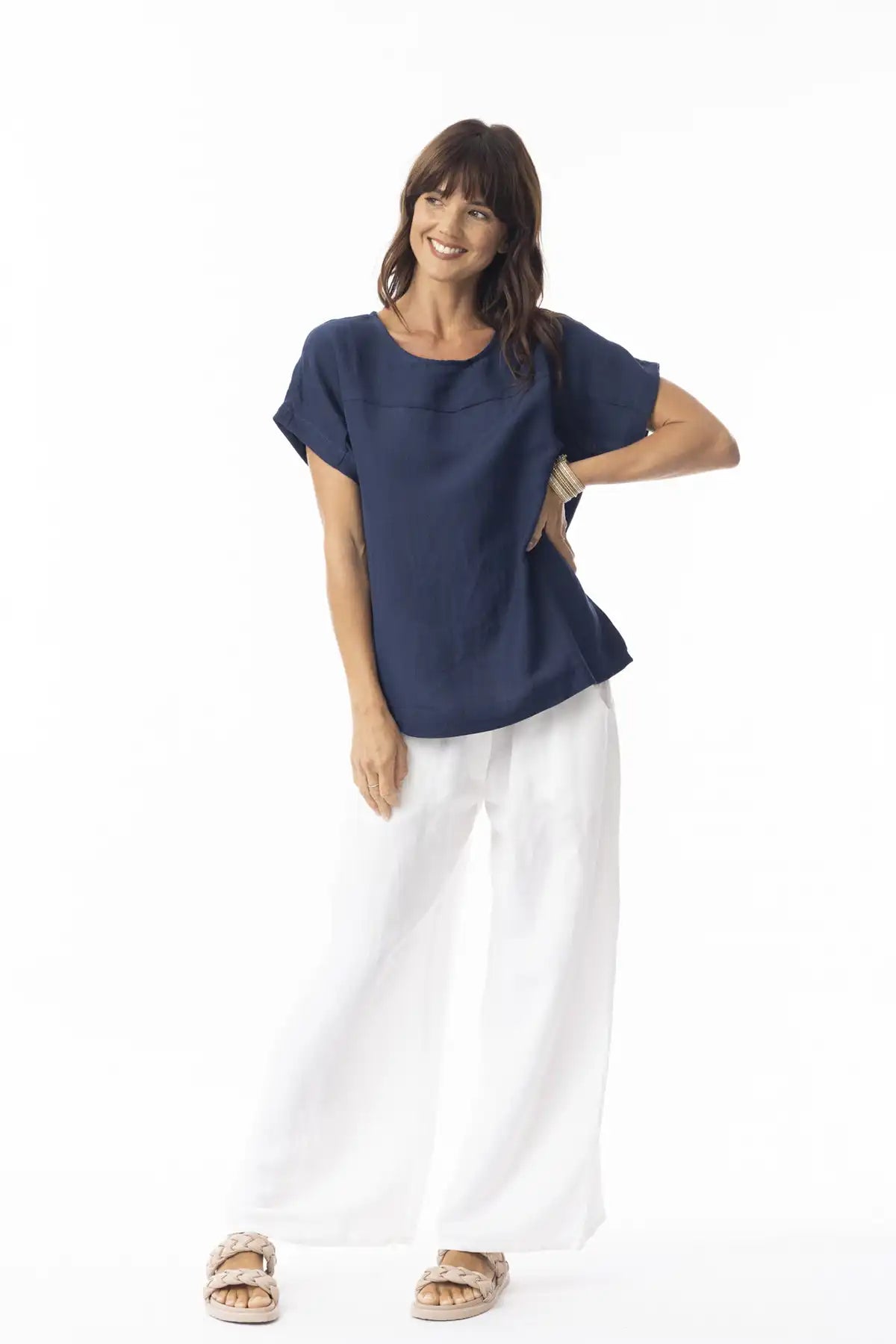 Woman wearing a Orientique Escape Linen Solid Boxy Navy Top and white pants on a white background