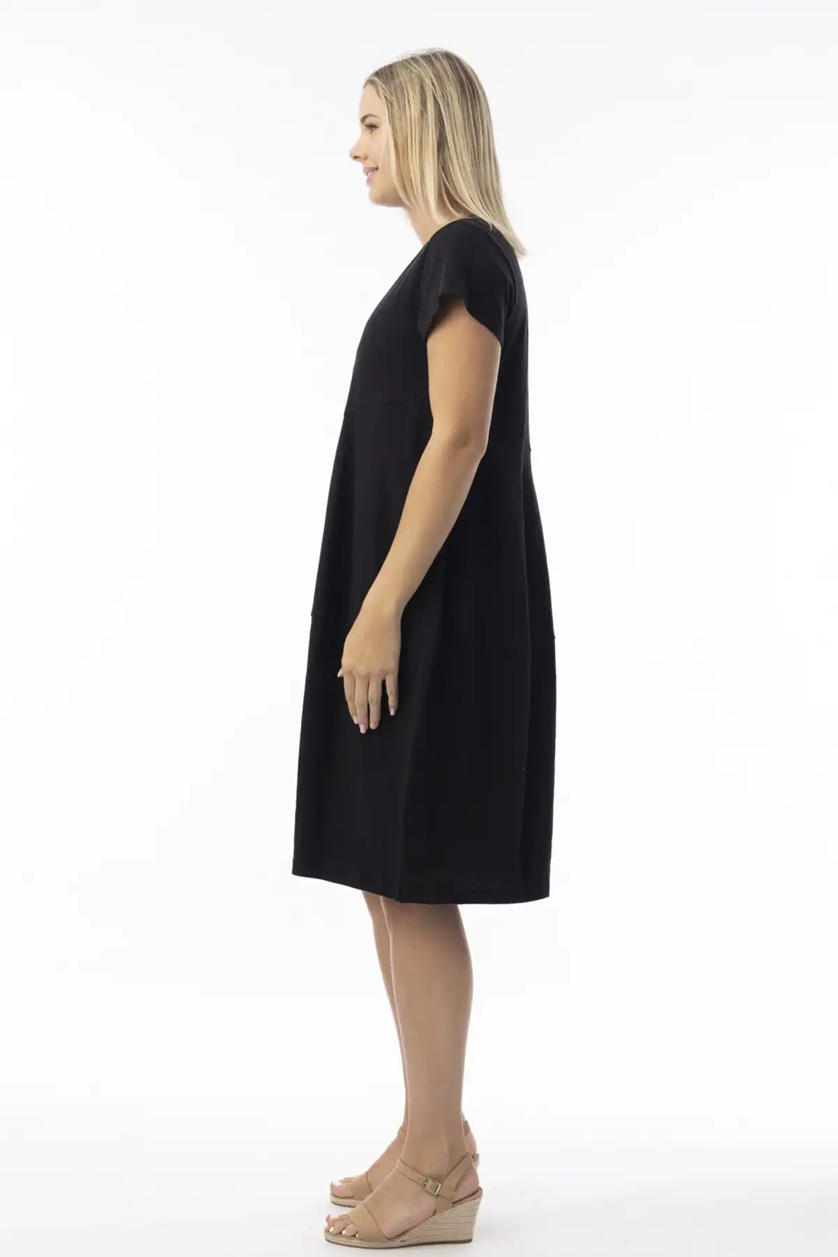 Woman wearing a Orientique Essentials Organic Cotton Bubble Dress in black sideon against a white background