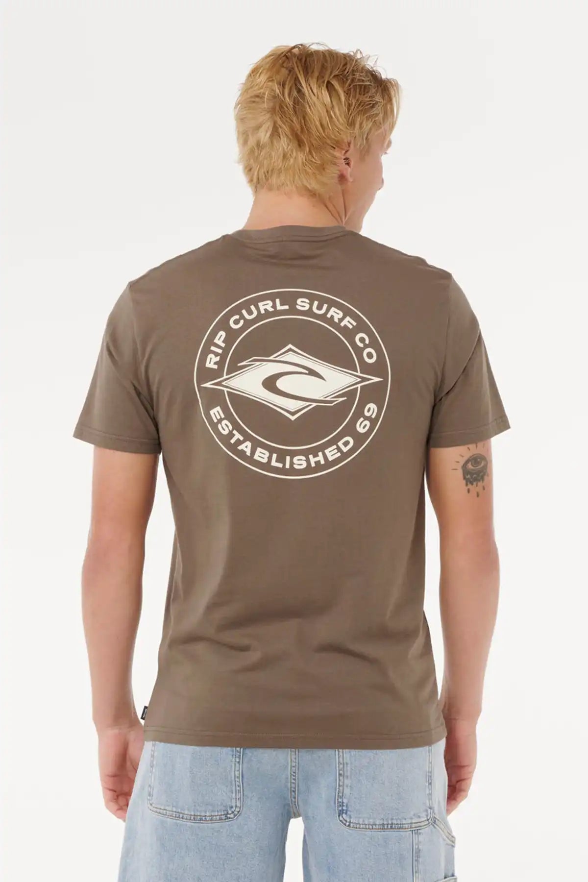 Person wearing a brown t-shirt with Rip Curl Surf Co logo on the back