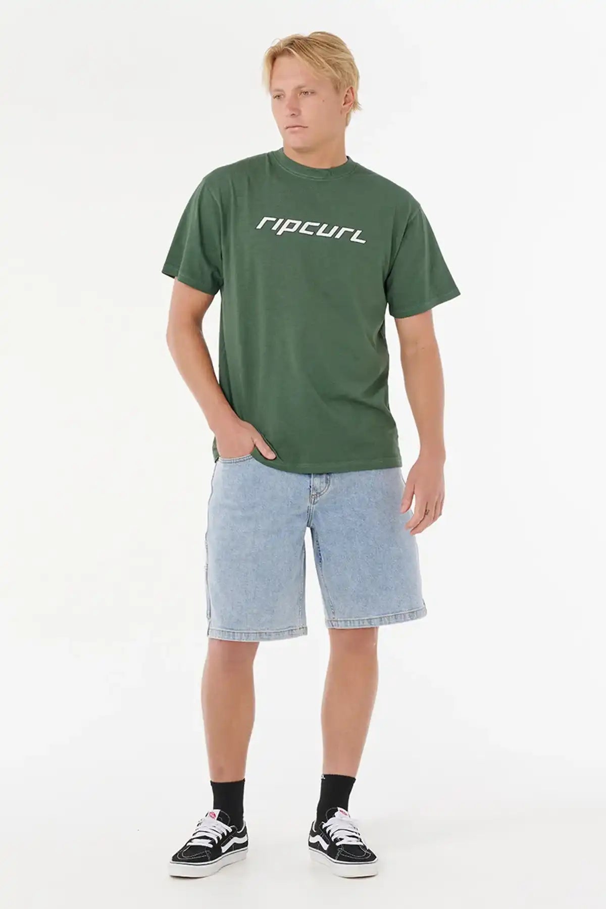 Person wearing a Rip Curl Nu Dosed Tee in Mountain Green and denim shorts on a white background