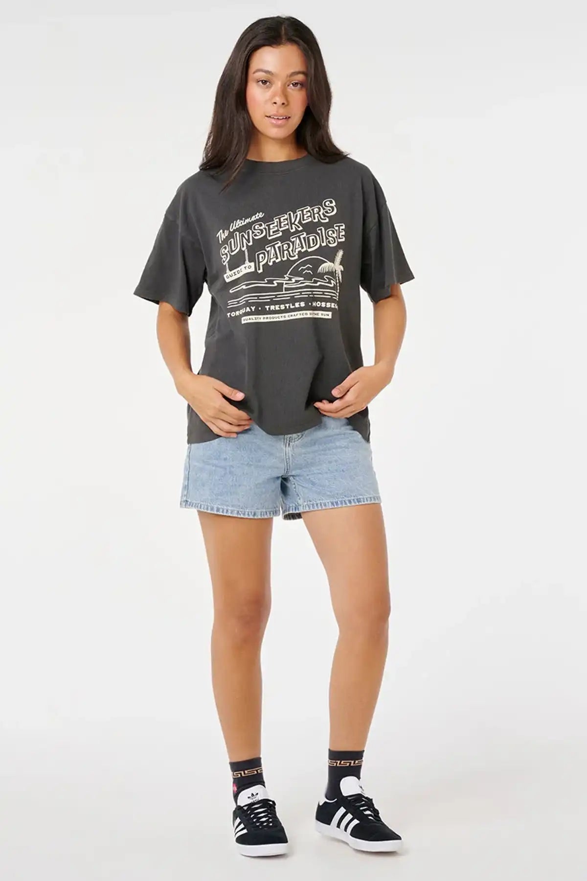 Person wearing a dark gray t-shirt with white text and light blue denim shorts on a white background