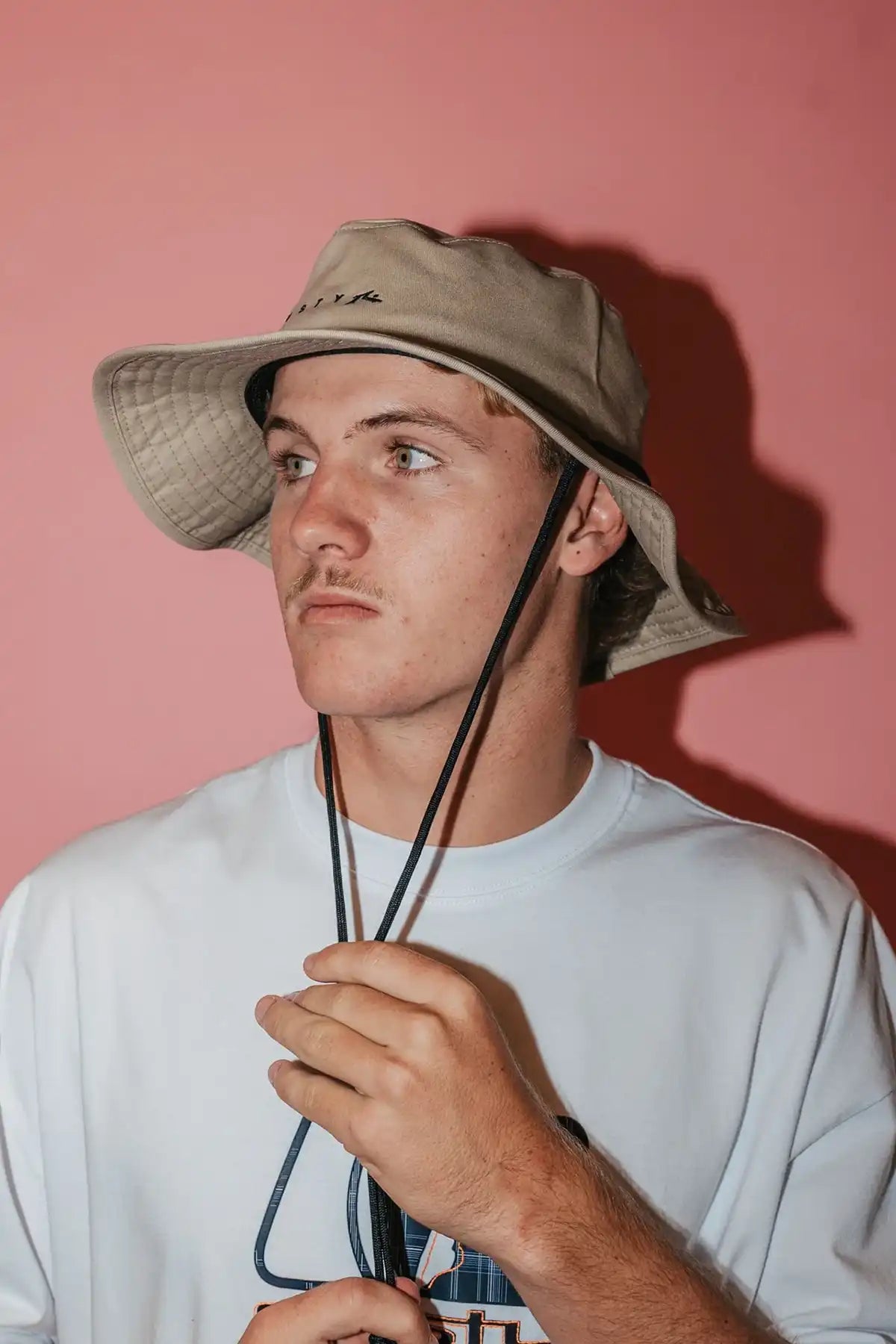 Person wearing a Rusty Bradman Wide Brim Hat in Abbey Stone against a pink background