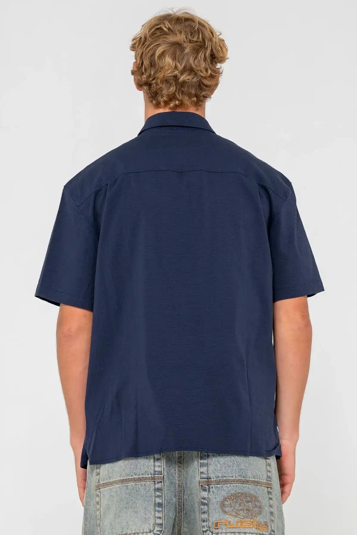 Person wearing a Navy Blue Rusty Giles Short Sleeve Shirt from behind on a white background