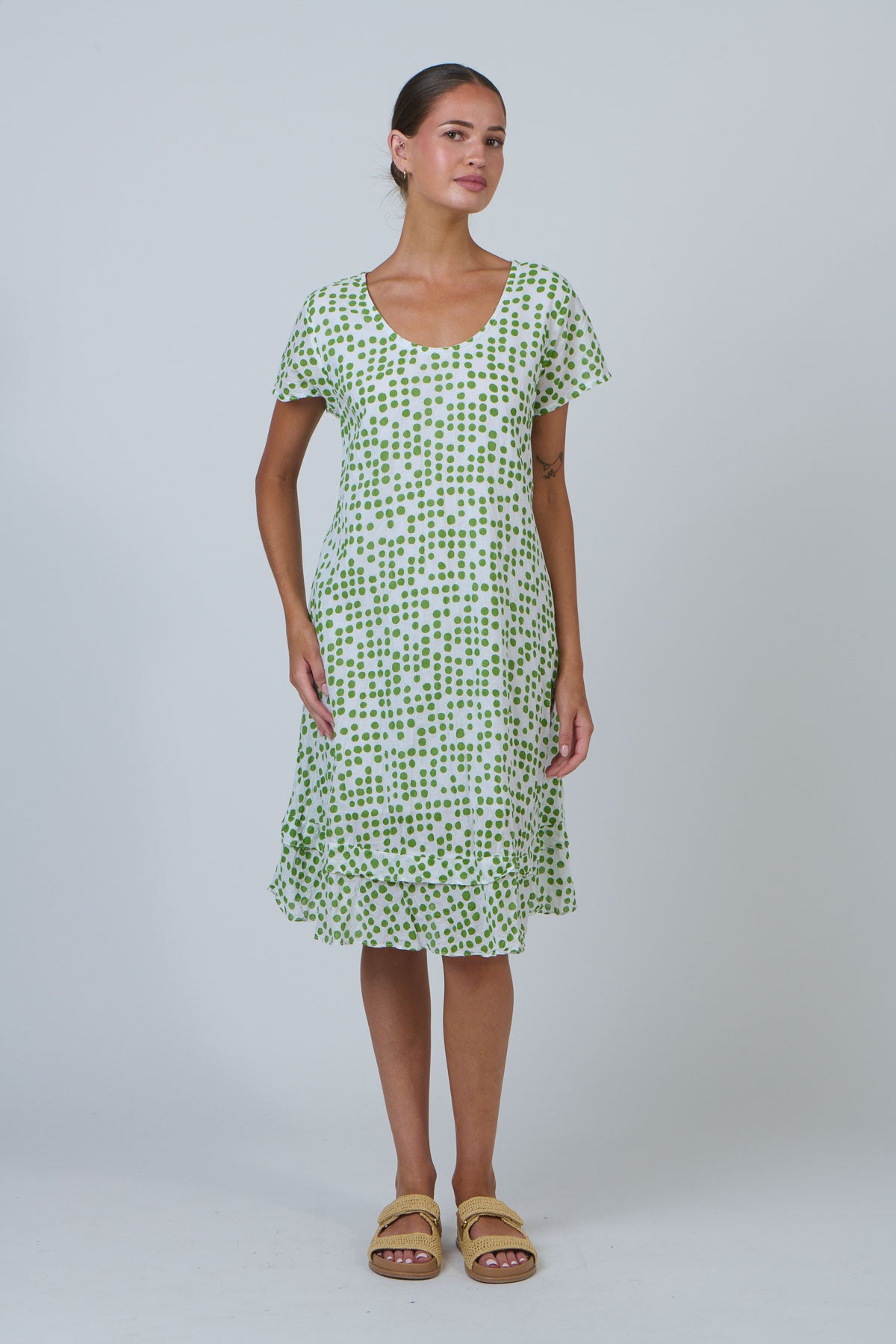 Woman wearing a green and white patterned dress on a plain background