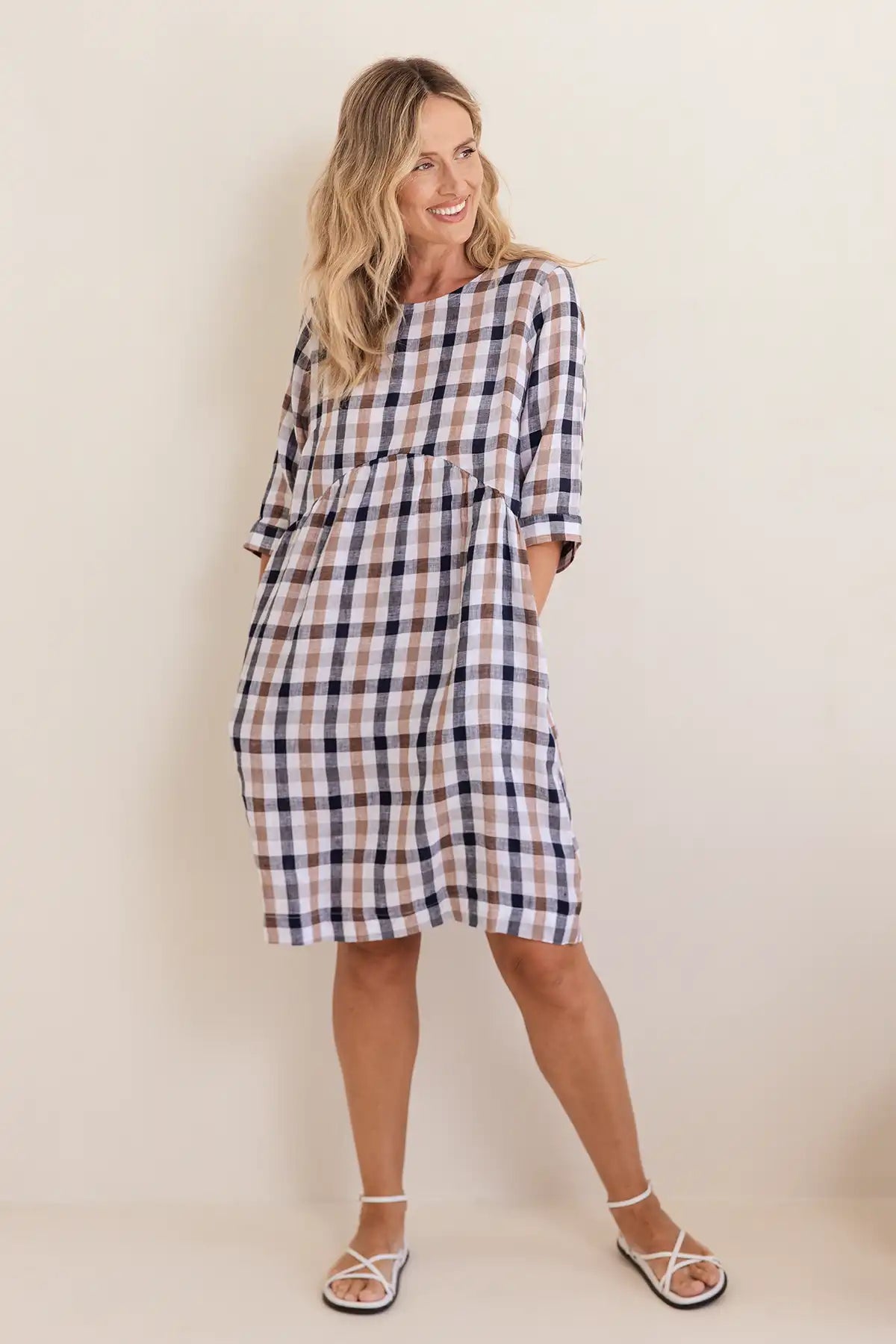 Woman wearing a plaid dress against a plain background