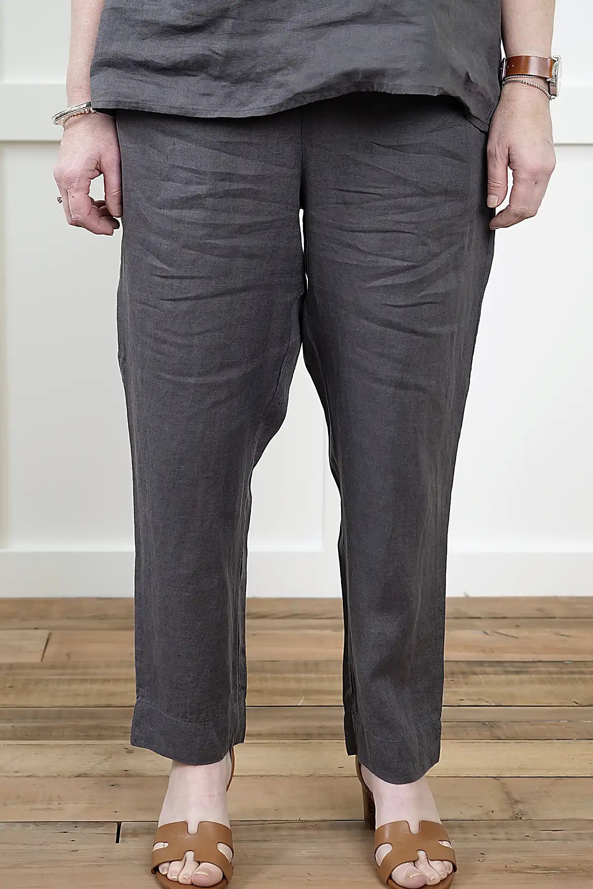 Person wearing See Saw Linen 7/8 Flat Front Pant and cowl neck top in Charcoal and a matching top front view on a wooden floor.