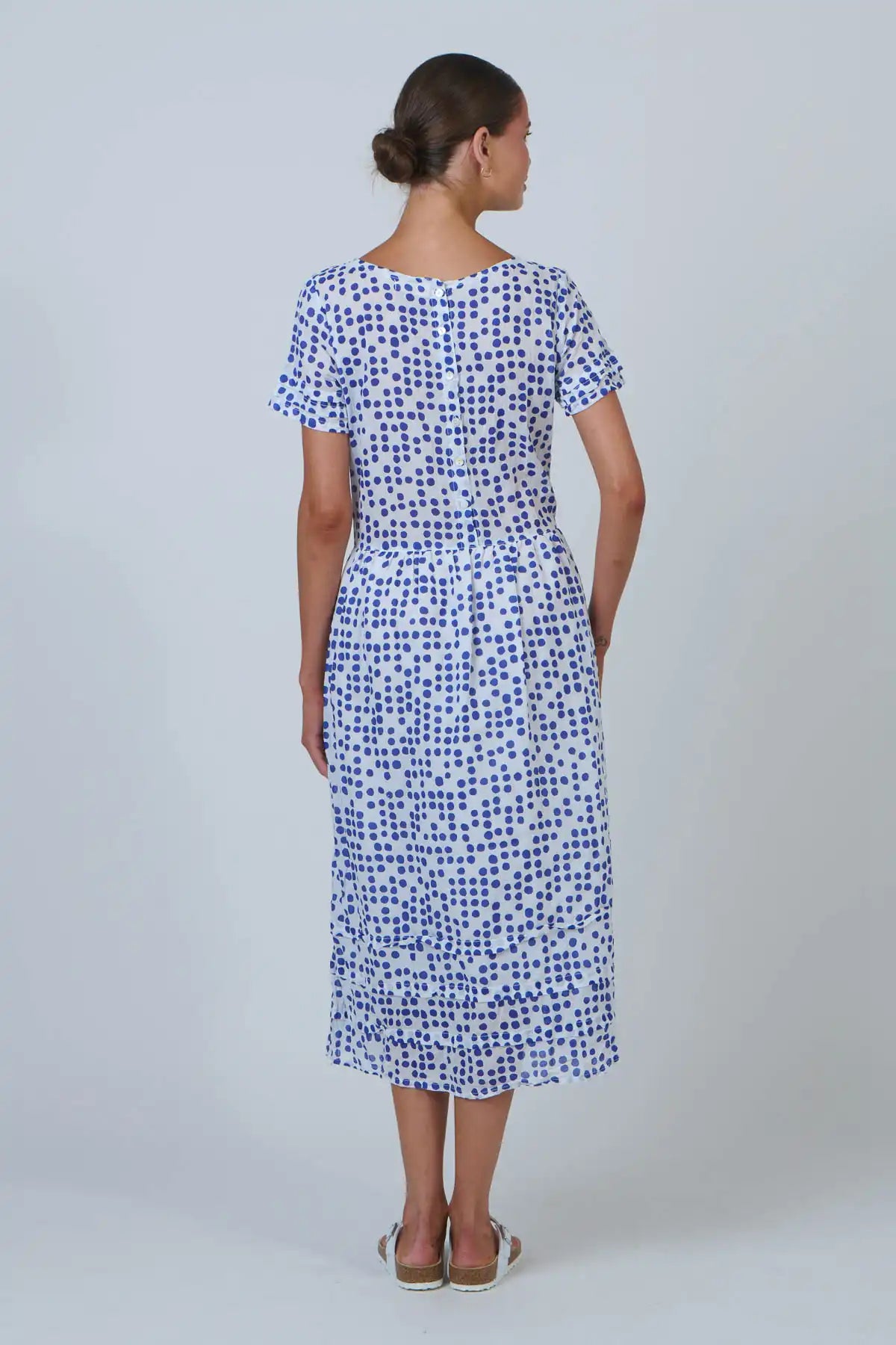 woman wearing a white cotton dress with blue dot print back view