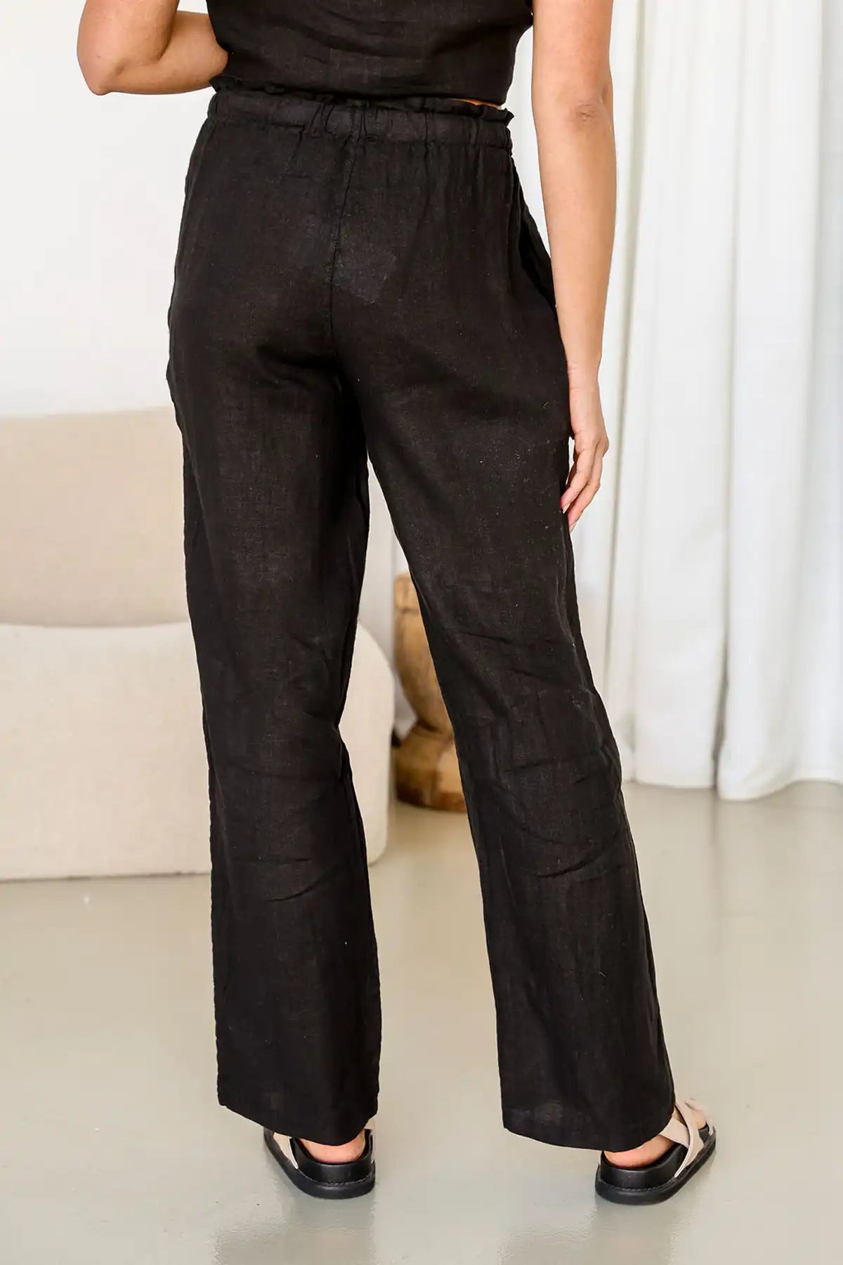 Person wearing Terra Lina Italian Linen pants in Slate standing against a white curtain background back view