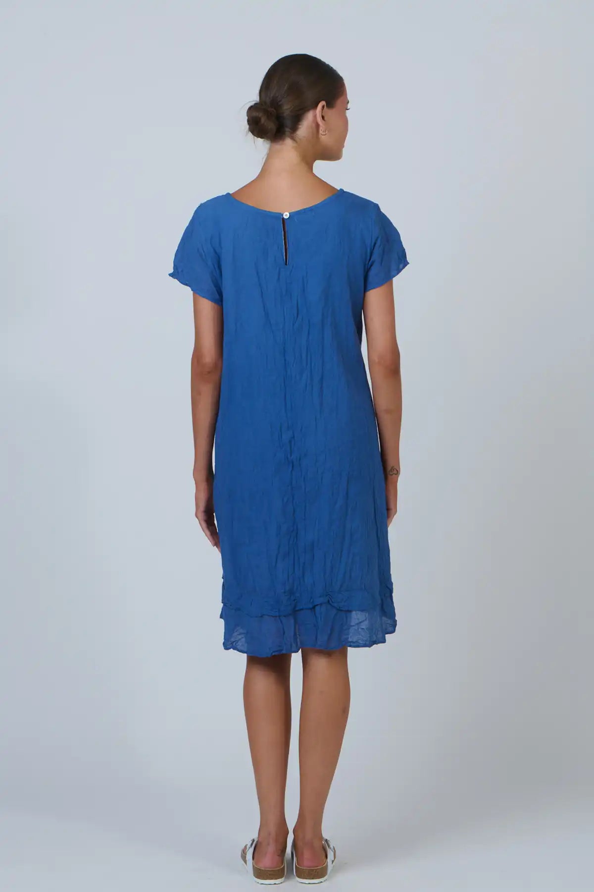 woman wearing the Tidal Pleat Cotton Dress in Ocean Blue against a white background view of the back