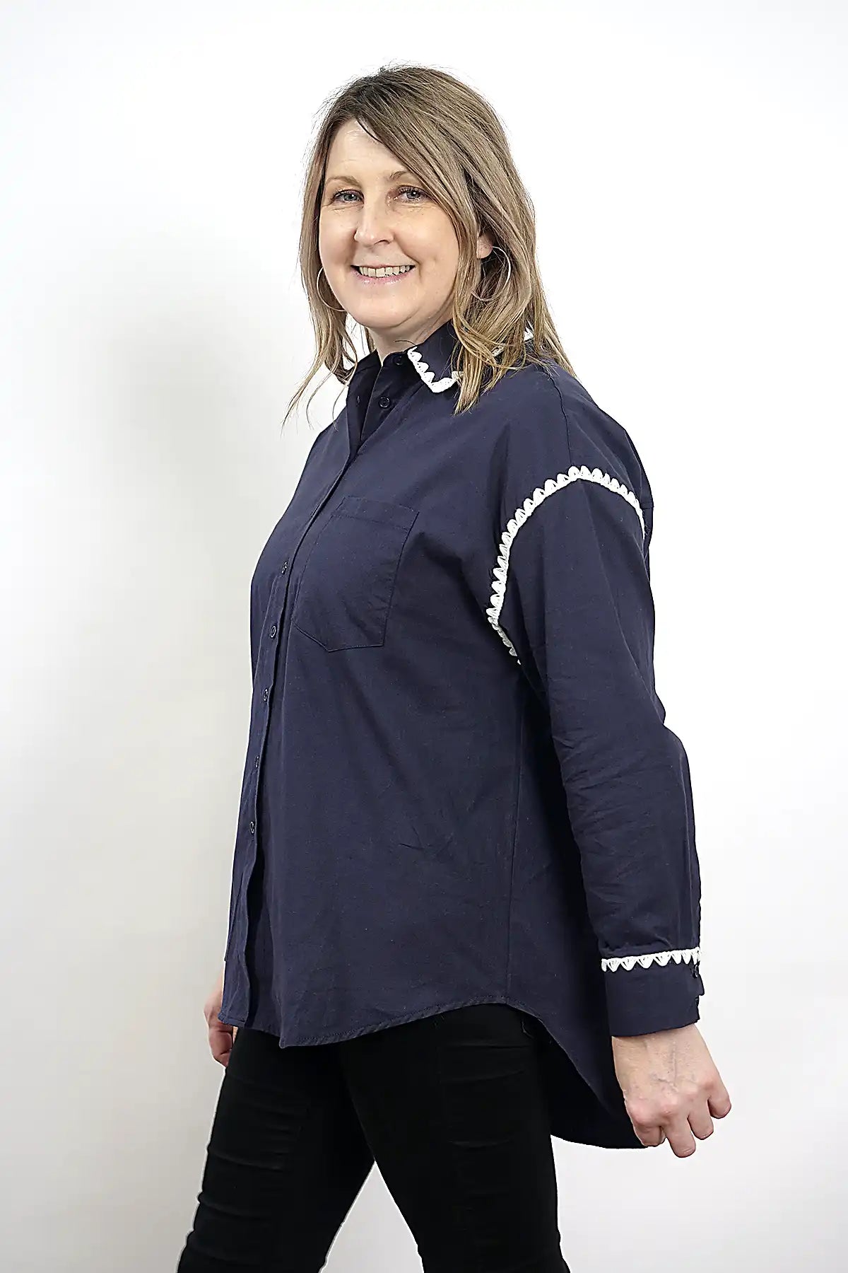 Woman wearing the Wren Long Sleeve Shirtin Navy with white trim on a white background, side view