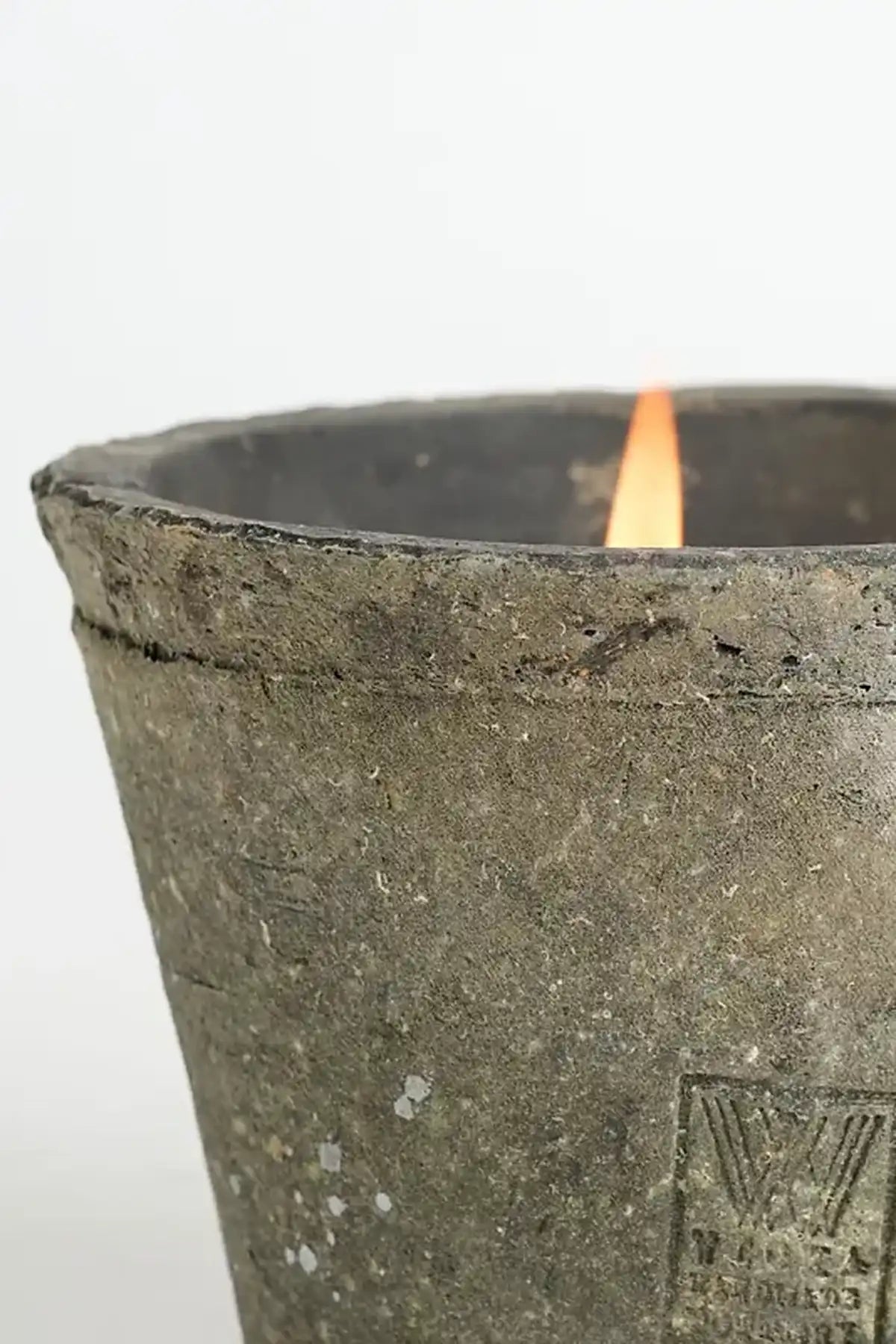 Ceramic candle holder with a lit candle on a white background