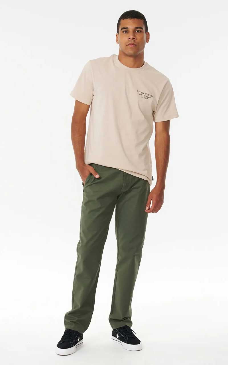 Man wearing rip curl searchers pant in green and cream tee i