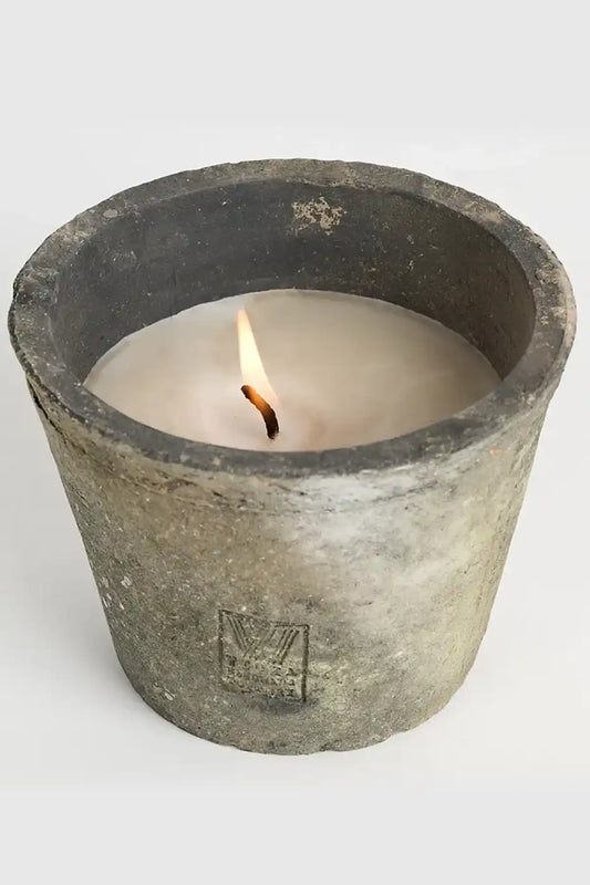 Candle in a rustic pottery holder on a white background