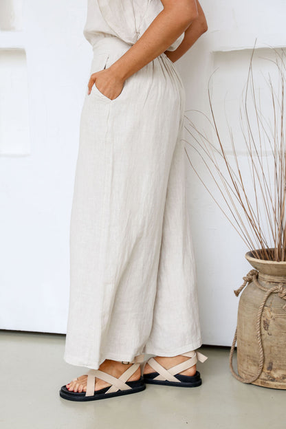 Person wearing sand pants and sandals with a neutral background