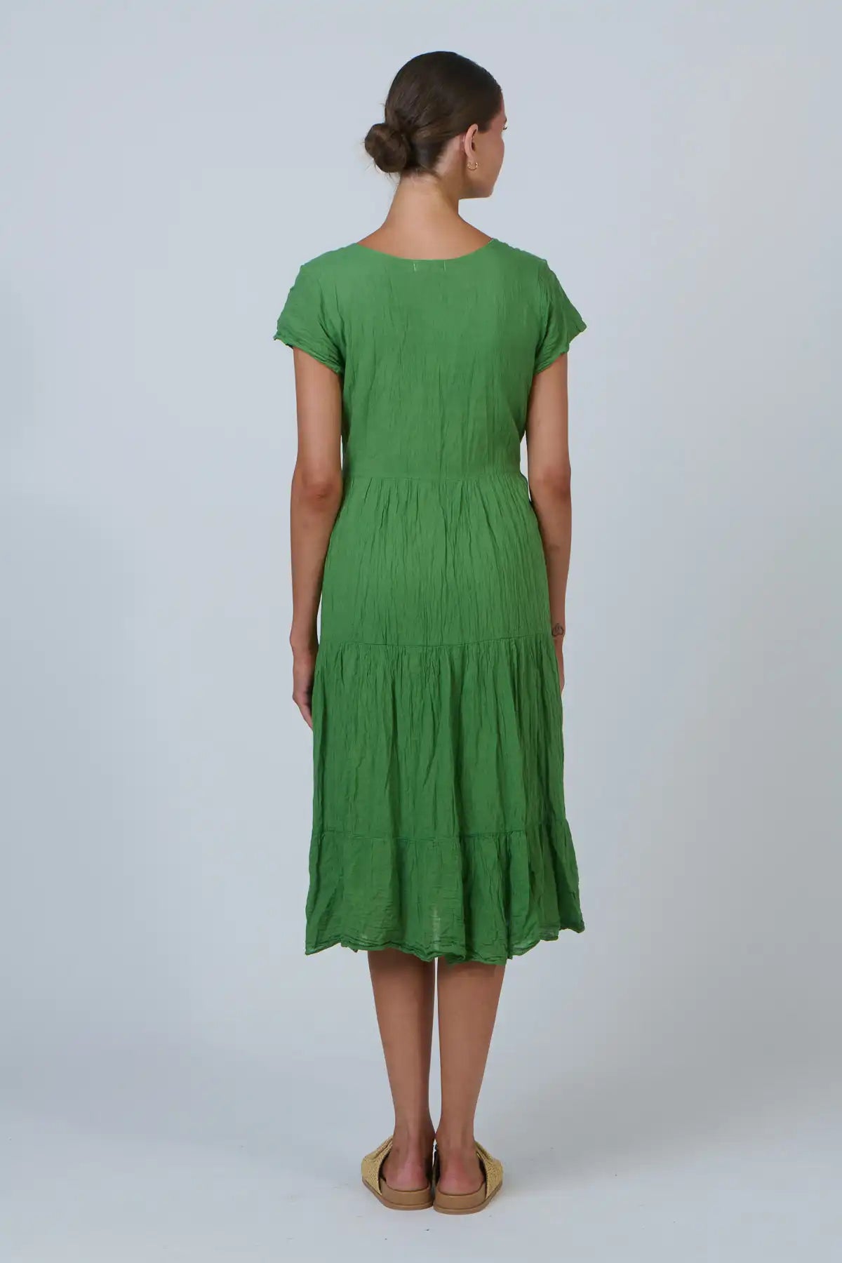 Woman wearing a green dress on a plain background back view