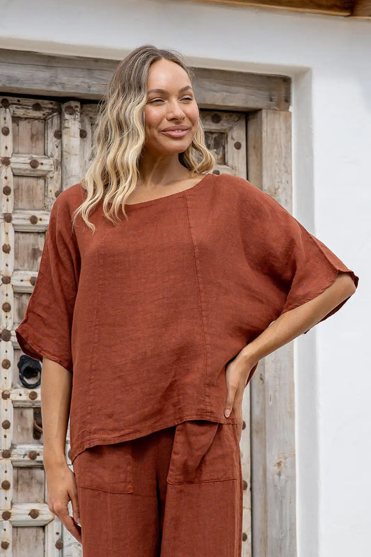 Woman wearing terracotta Italian linen top with boat neckline and elbow sleeves