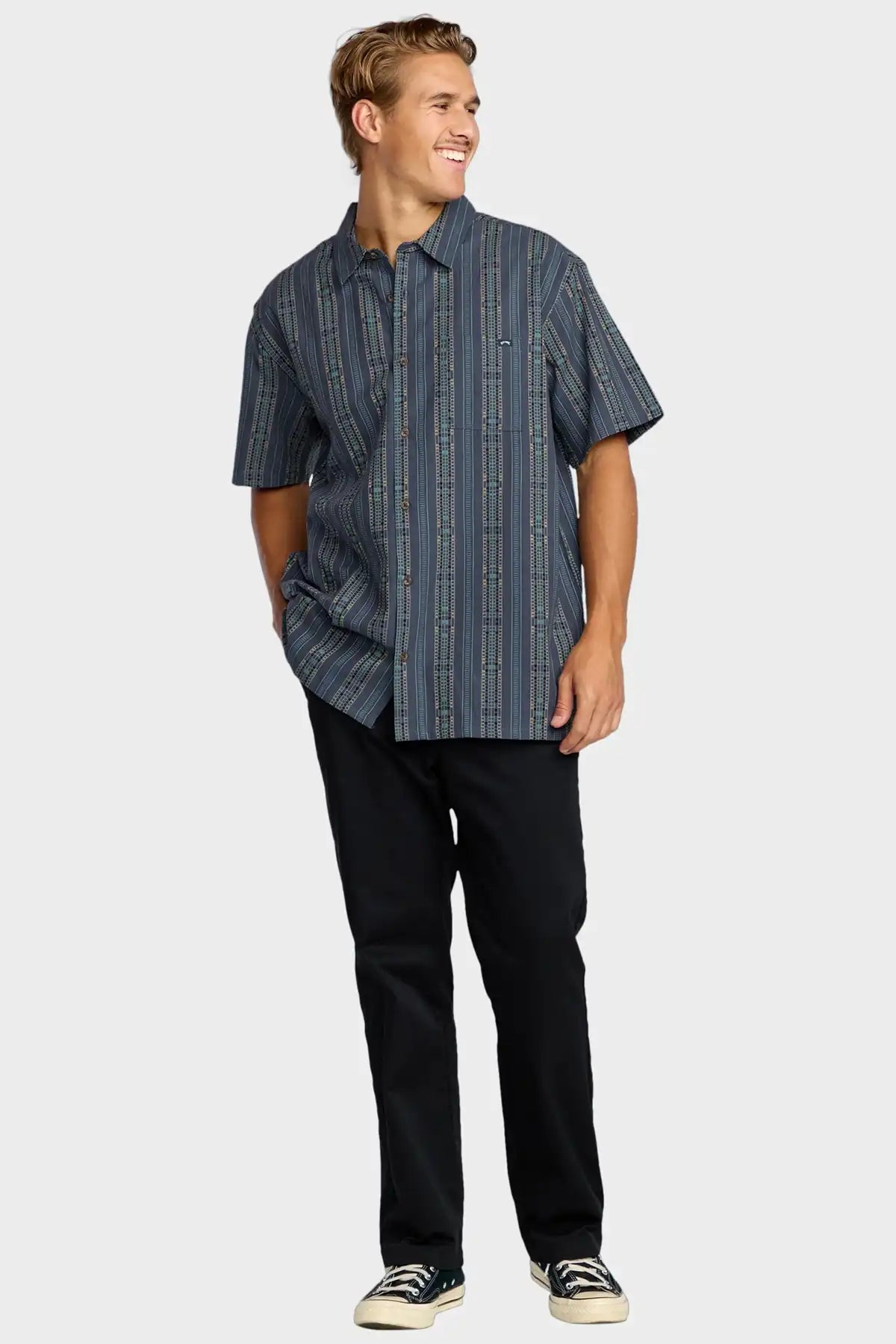 Man wearing a blue Billabong striped shirt and black pants on a white background