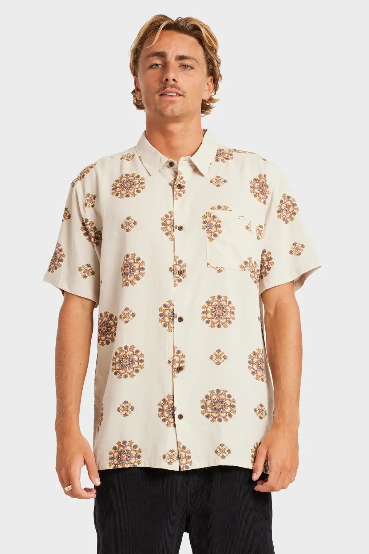 Man wearing a Billabong cream-colored shirt with brown floral pattern on a white background