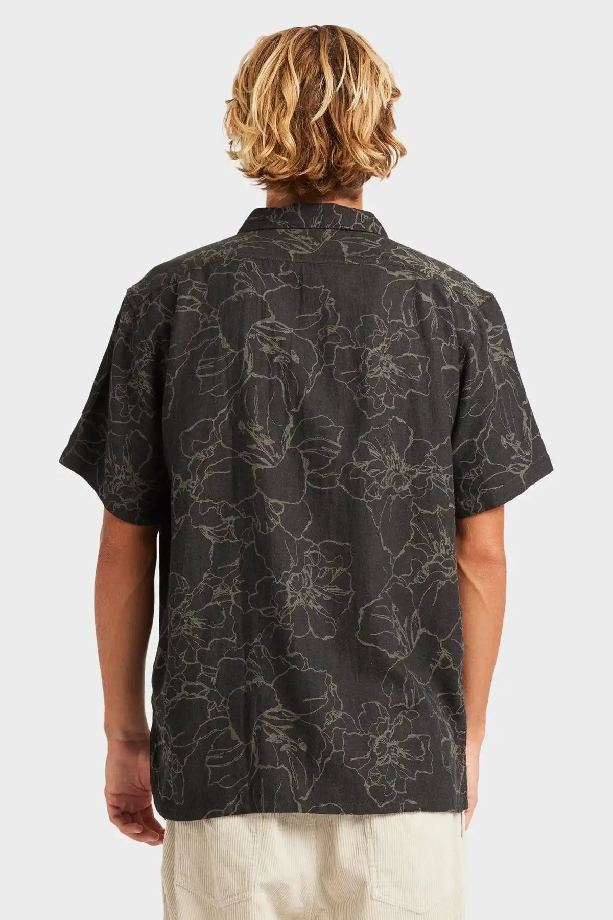 Person wearing a Billabong black patterned shirt on a white background